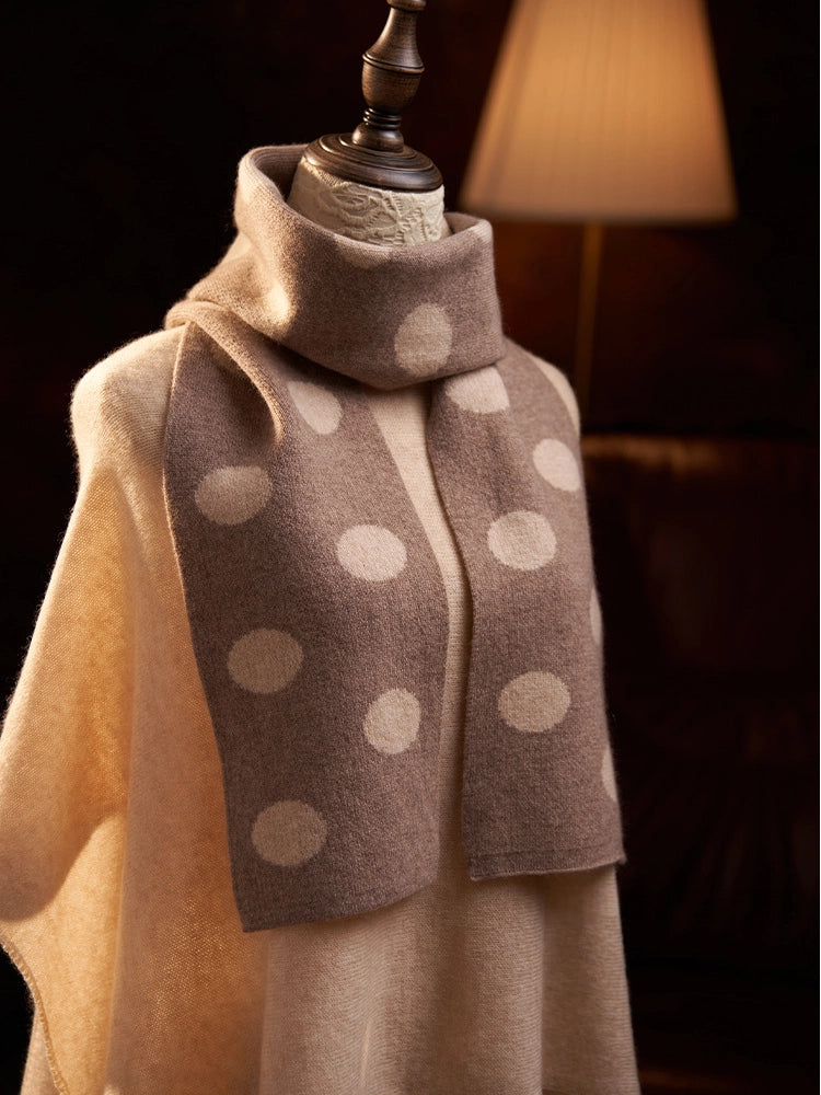 Angled close-up of a camel cashmere scarf showing cream polka dots and a fuzzy texture.
