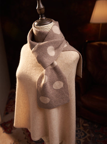 Camel polka dot cashmere scarf tied in a loose front knot over a camel sweater on a mannequin.