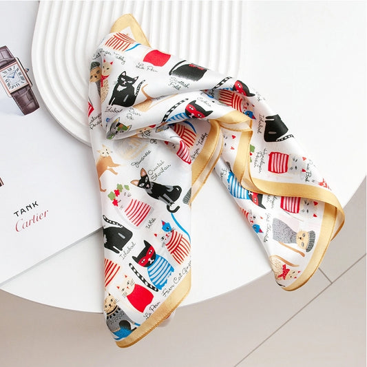 Small silk square scarf with cartoon cat print, styled as a chic neckerchief and bag accessory.