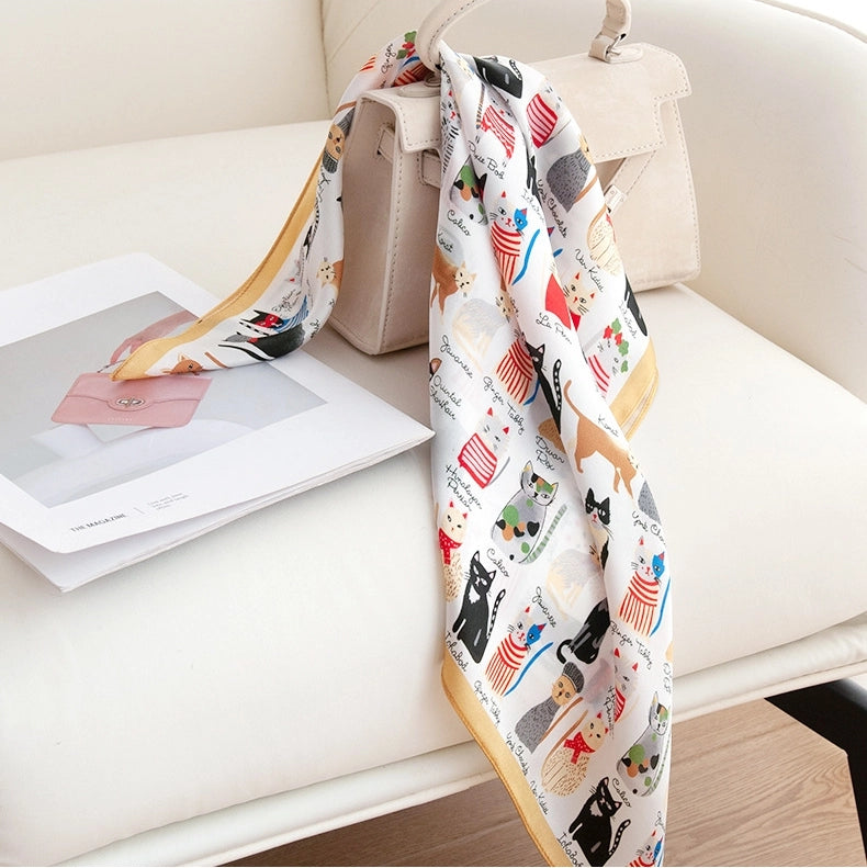 Cat print silk neckerchief draped on a sofa, designed as a versatile small silk scarf accessory.