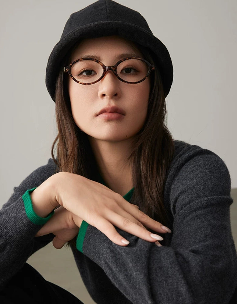 Front view of a woman in glasses wearing a charcoal gray rolled brim dome hat