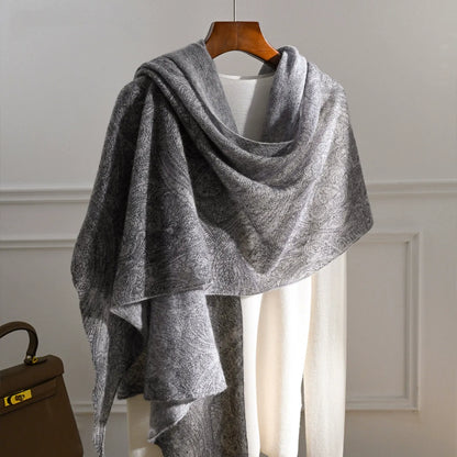 Charcoal grey cashmere scarf with a tonal paisley pattern draped over a cream knit top.