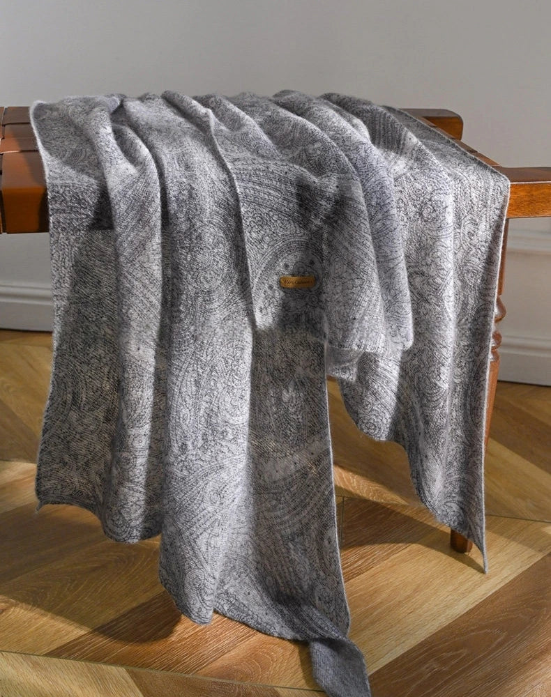 Charcoal grey lightweight cashmere scarf draped over a wooden chair, showing its length and flowing folds.