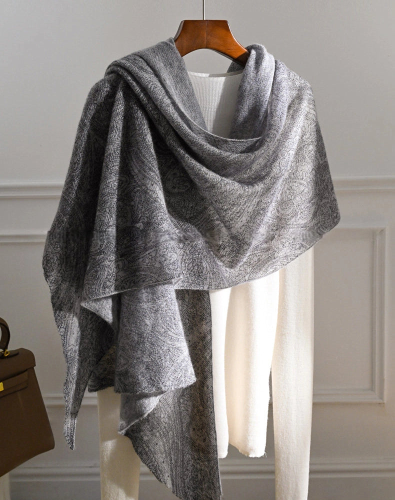 Charcoal grey cashmere shawl with an asymmetrical drape and long hanging ends over a cream top.