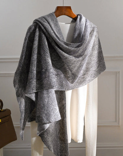 Charcoal grey cashmere shawl with an asymmetrical drape and long hanging ends over a cream top.