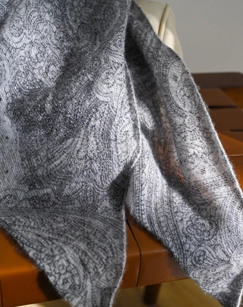 Close-up of a charcoal grey cashmere scarf showing tonal paisley motifs and a softly textured surface.