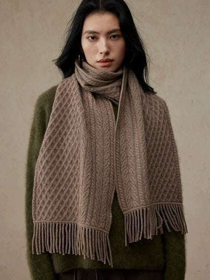 Coffee brown cable knit scarf with fringed ends, wrapped around a model's neck over an olive sweater.