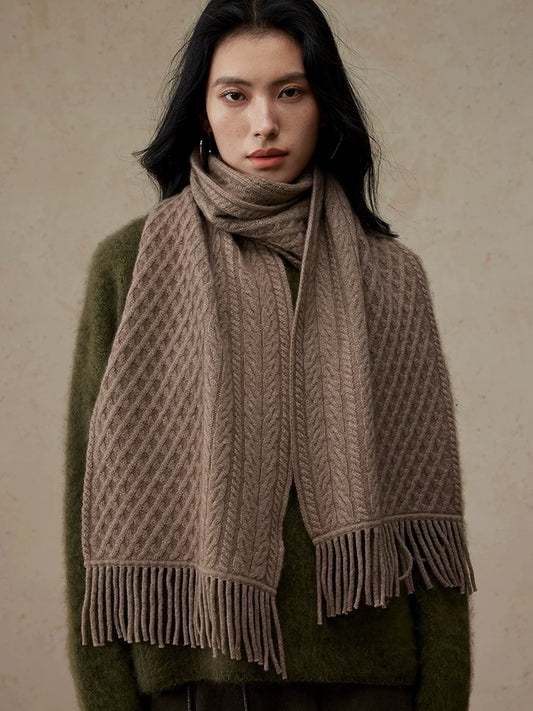 Coffee brown cable knit scarf with fringed ends, wrapped around a model's neck over an olive sweater.