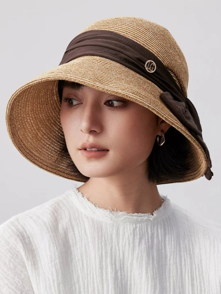 Coffee wide brim straw sun hat with bow ribbon accent, designed for sun protection, travel and refined summer outfits.