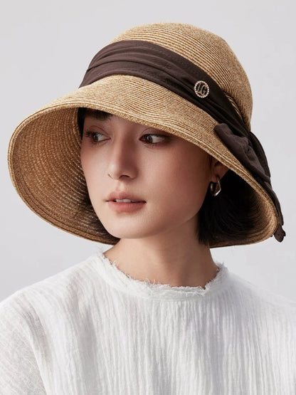 Coffee wide brim straw sun hat with bow ribbon accent, designed for sun protection, travel and refined summer outfits.