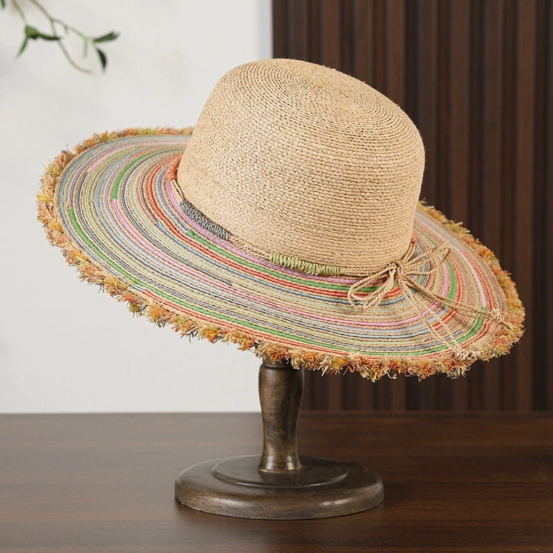 Colorful woven raffia beach hat with wide brim, frayed edge, and beige straw crown.