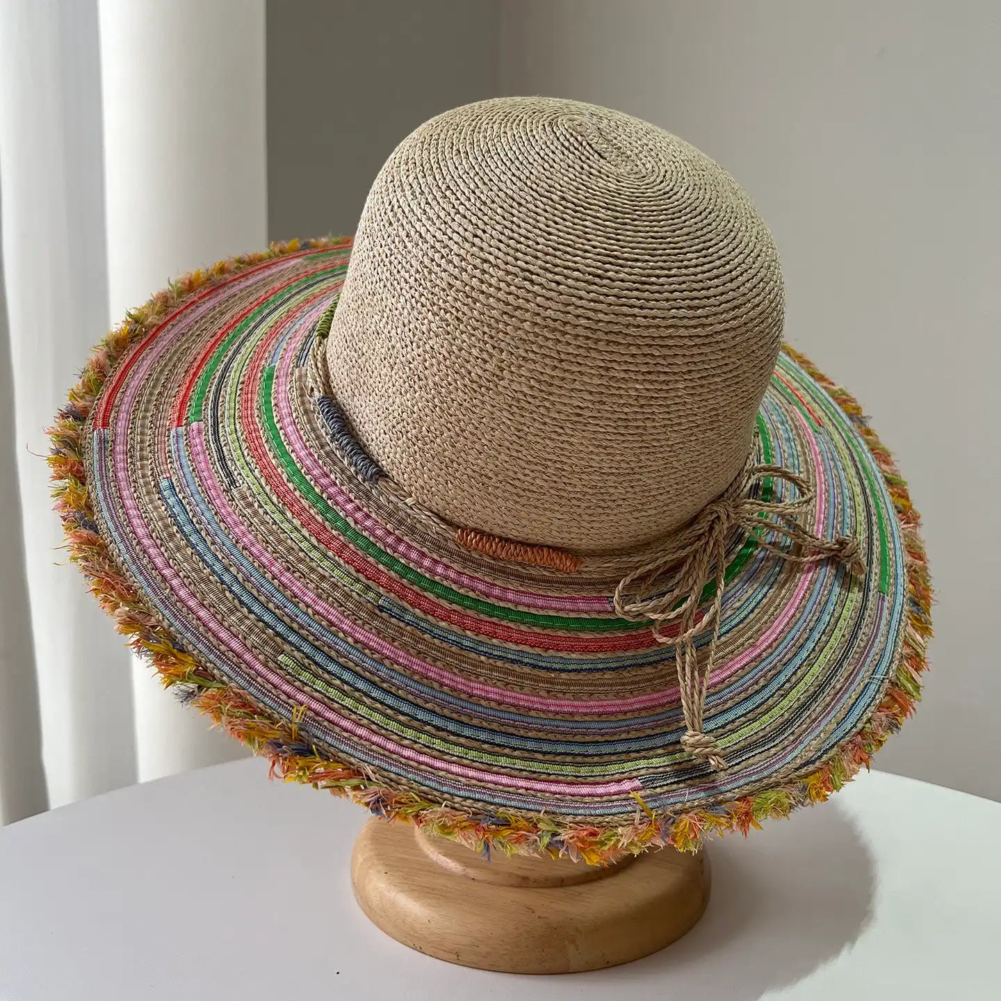Natural beige raffia straw sun hat with multicolor woven brim and tie detail.