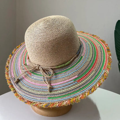 Top view of beige raffia wide brim sun hat with colorful striped brim and frayed edge.