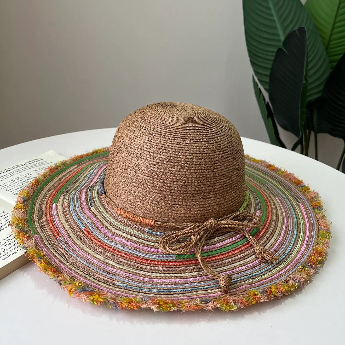 Warm brown raffia wide brim sun hat with colorful striped brim and boho frayed edge.