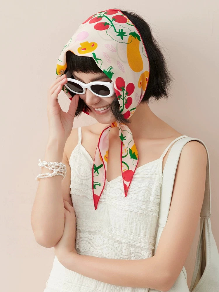 Colorful silk triangle scarf worn as a headscarf with white summer outfit and sunglasses
