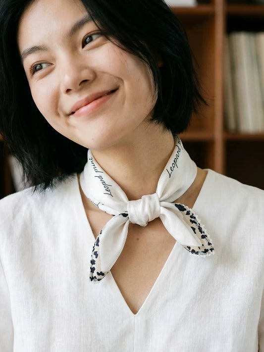 Creamy ivory mulberry silk scarf tied at the neck with a white V-neck blouse