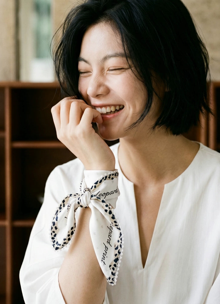 Woman in a white blouse wearing a creamy ivory silk scarf in a relaxed front knot