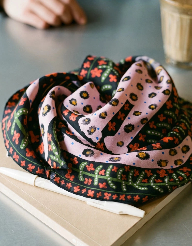 Folded crimson red leopard floral mulberry silk scarf displayed on a book