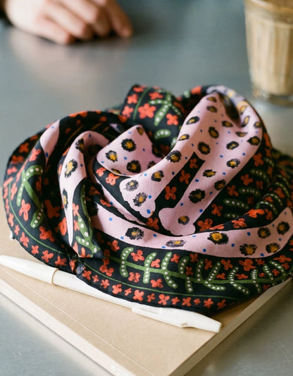 Folded crimson red leopard floral mulberry silk scarf displayed on a book