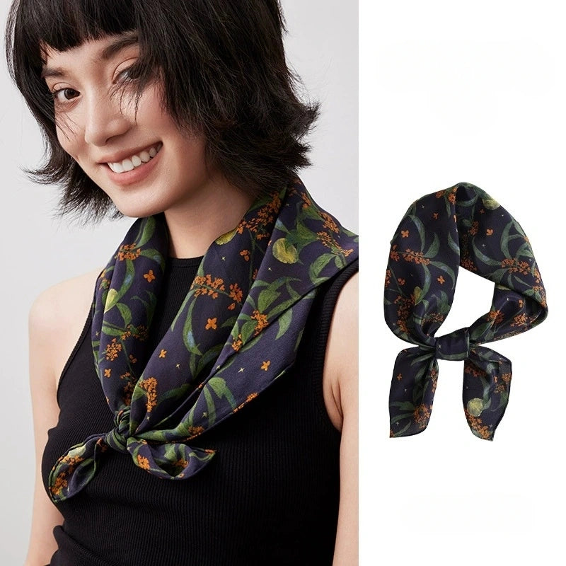 An elegant navy blue osmanthus-print silk scarf, crafted from 100% mulberry silk, showcases its vibrant floral design and smooth texture.