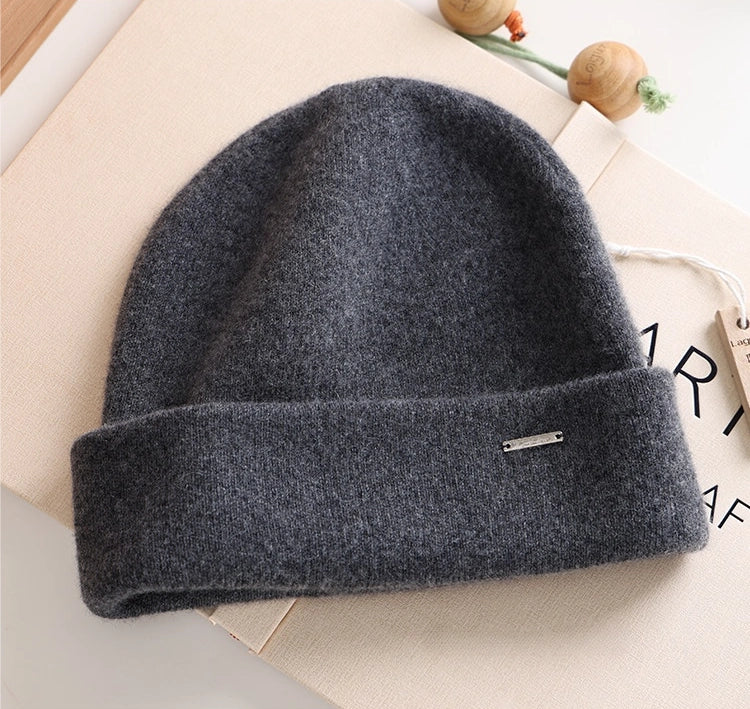 Dark gray 100% cashmere cuffed beanie with a small metal accent in a flat lay