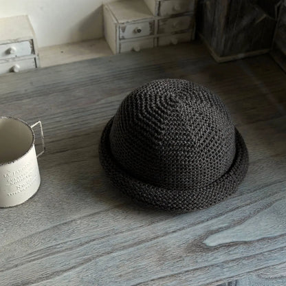 Dark gray wool blend knit beanie with a rounded dome crown and rolled brim on a wooden table