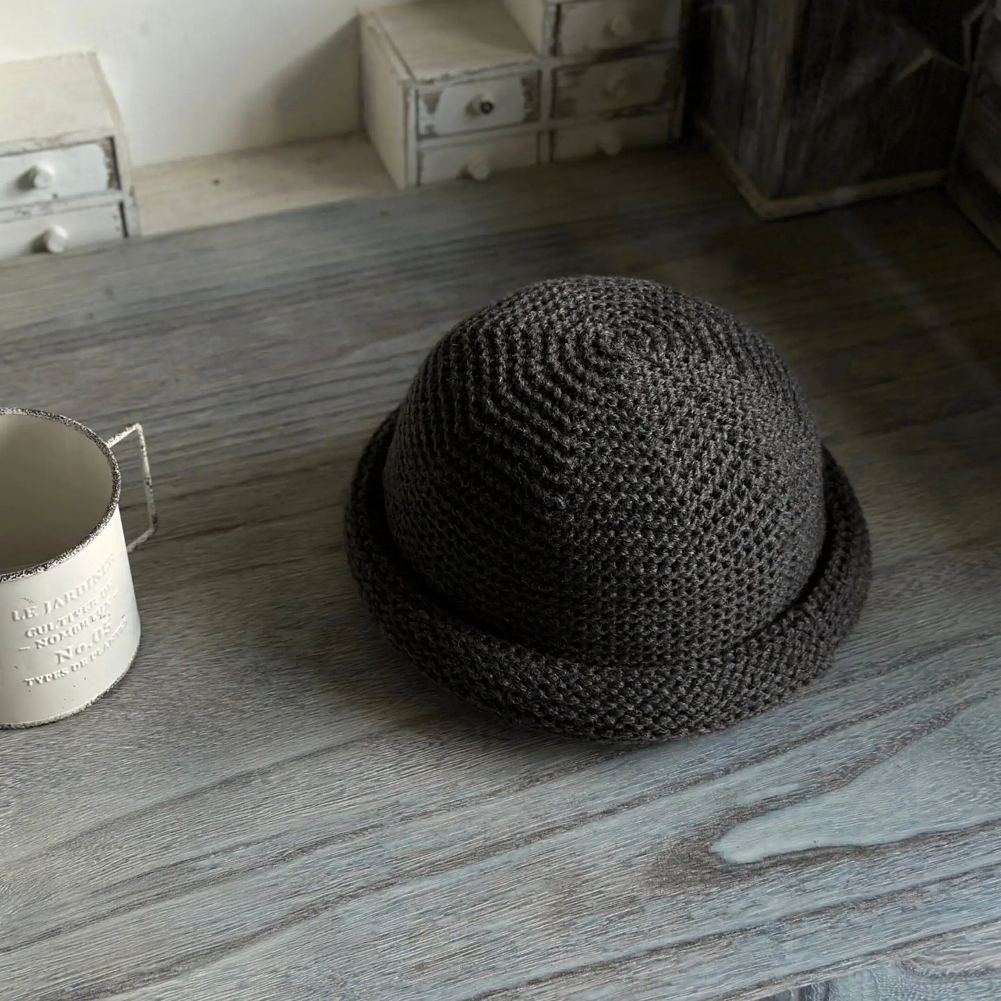 Three-quarter view of a dark gray rolled brim knit hat with textured wool blend stitching