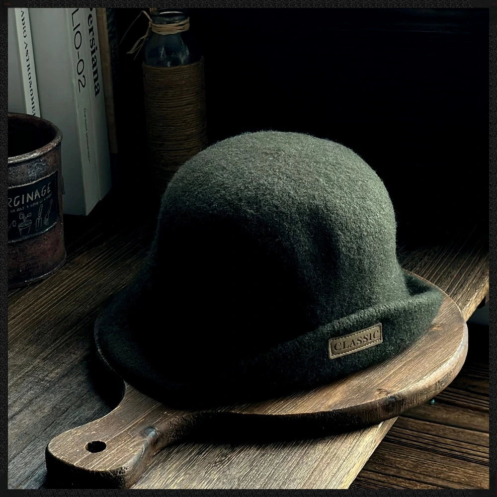 Dark green women's wool felt cloche hat with a rounded crown, rolled brim and small logo patch