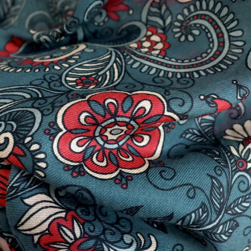 Detailed view of red floral medallions and paisley print on the dark green wool scarf