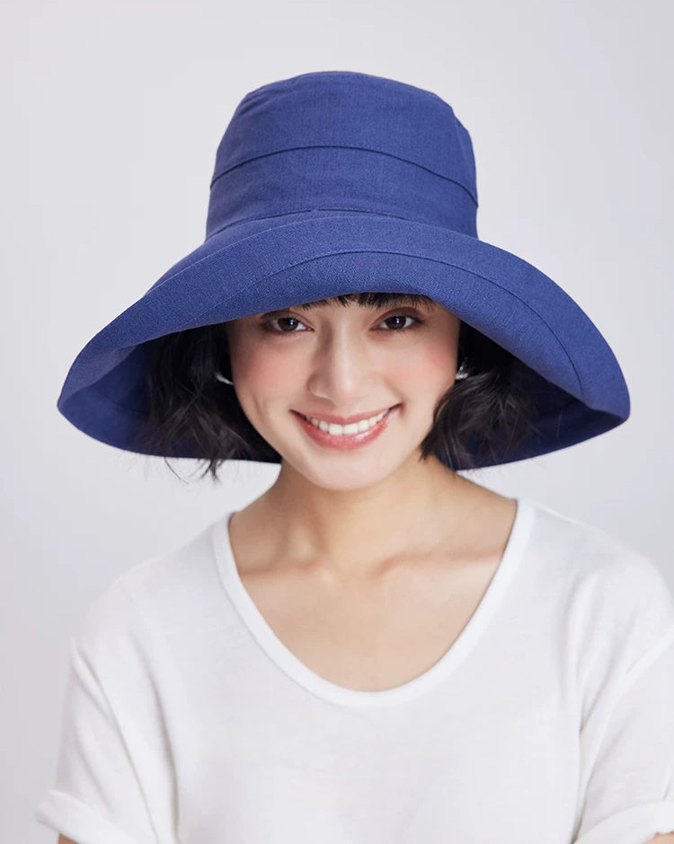 Front view of a deep blue linen cotton wide brim sun hat styled with a white summer top