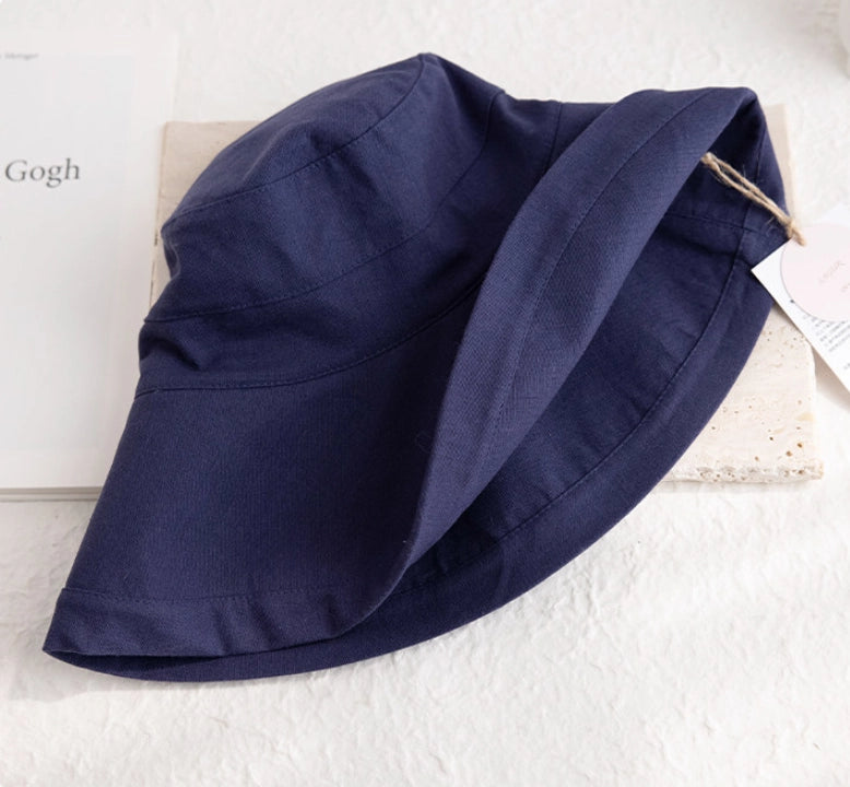 Close-up of a foldable deep blue linen cotton sun hat showing the soft brim and natural fabric texture