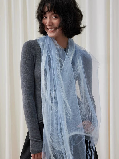 Lightweight blue mulberry silk scarf draped loosely around the neck with long fringed ends