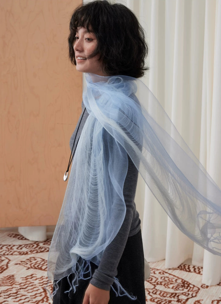 Flowing distant mountain blue silk fringe scarf styled over a charcoal outfit