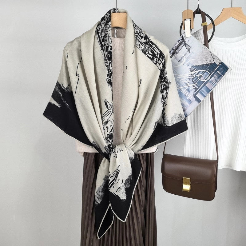 Black and ivory Paris print scarf styled in a front-knot wrap over a neutral pleated outfit