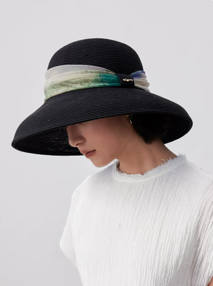 Elegant black wide brim sun hat with scarf ribbon, front side view on woman.