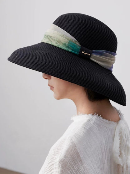 Side profile of black wide brim sun hat with artistic scarf ribbon detail.