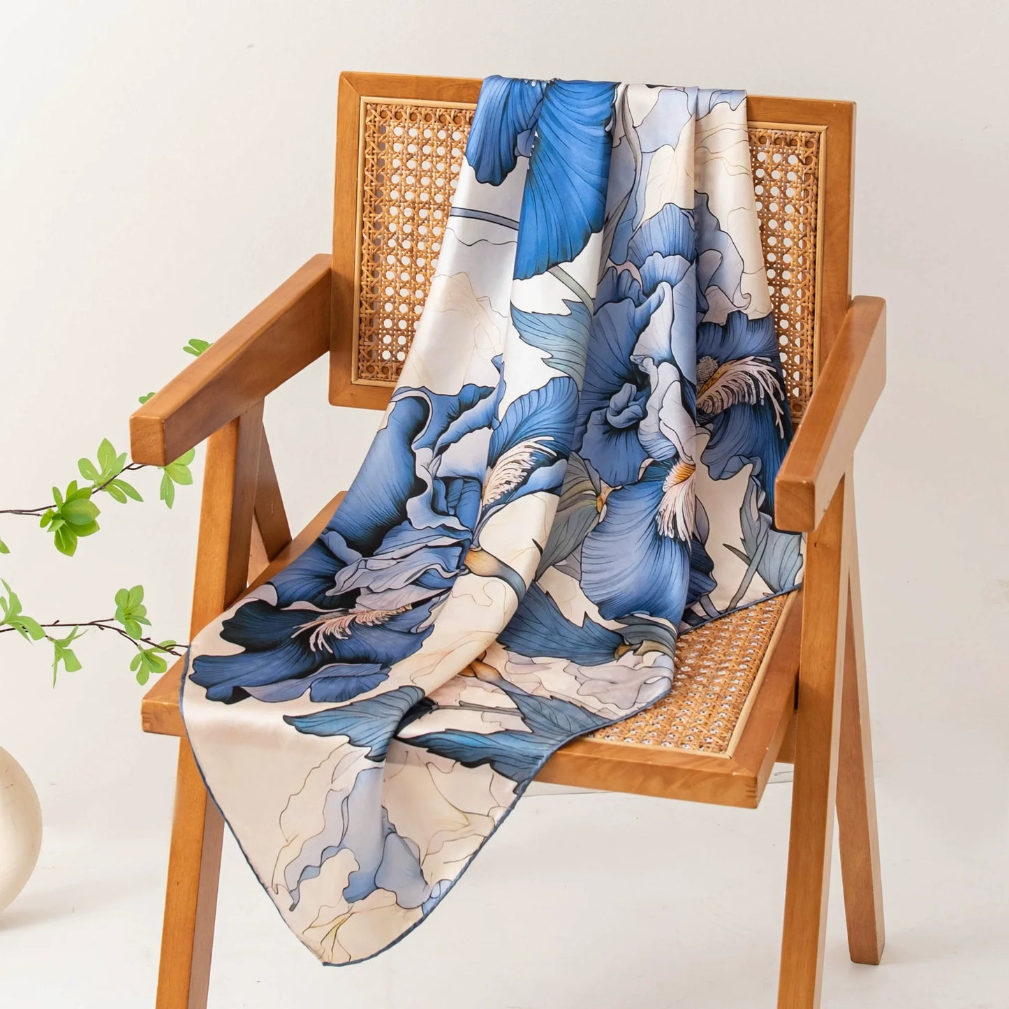 Elegant blue floral silk scarf draped over wooden chair in warm natural light