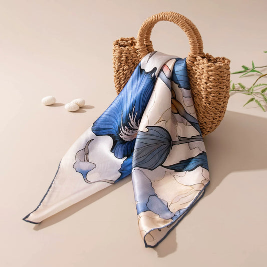 Blue floral mulberry silk scarf styled on woven handbag for vacation outfit inspiration