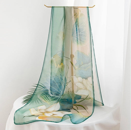 Elegant lotus print long silk scarf displayed on a soft white fabric backdrop