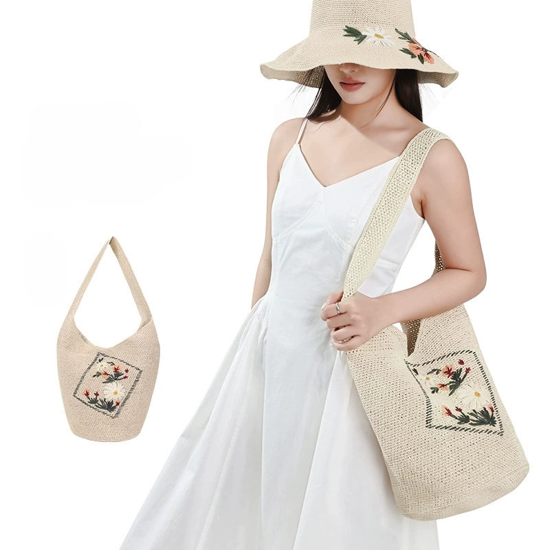 Woman carrying an ivory floral embroidered woven straw shoulder bag with matching wide brim sun hat for summer vacation outfits
