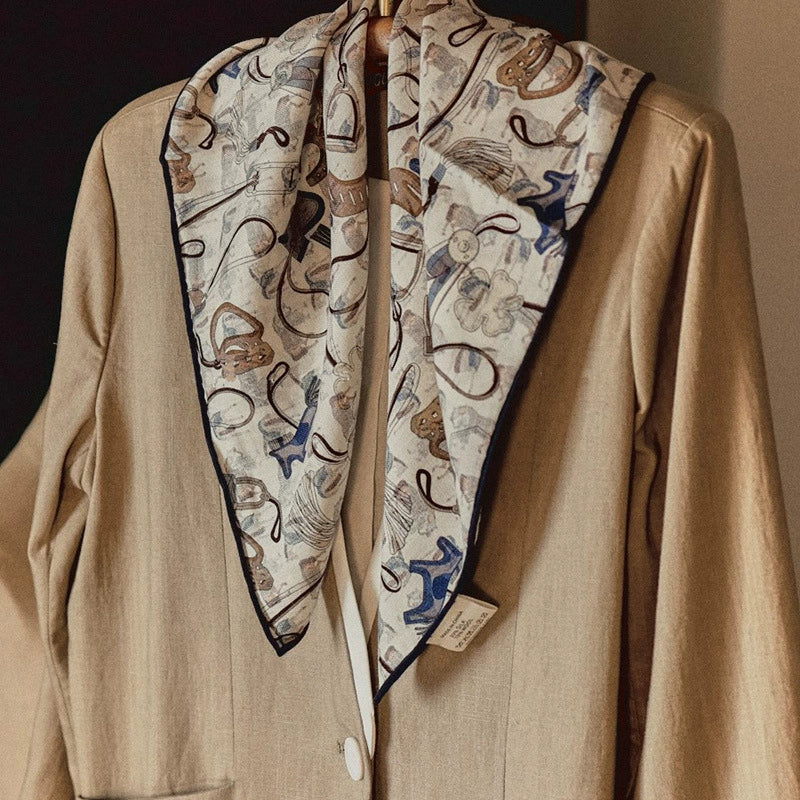 Silk wool square scarf with horse tack print worn on beige coat, elegant styling look