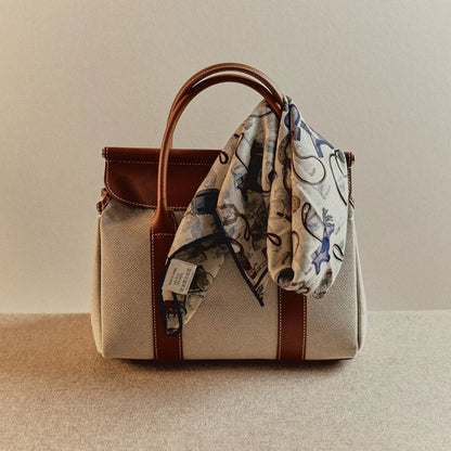 Square silk wool scarf tied on leather handle bag, horse tack accessories print detail