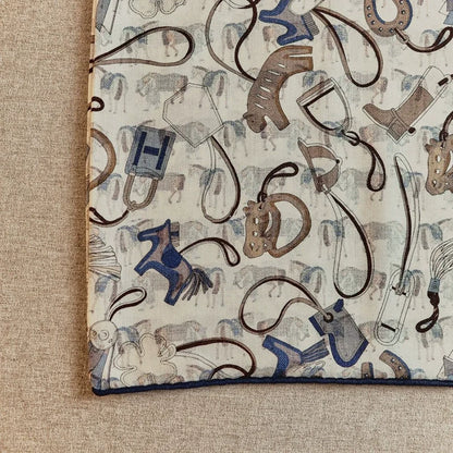 Close-up silk wool scarf fabric showing horse tack and accessories pattern detail