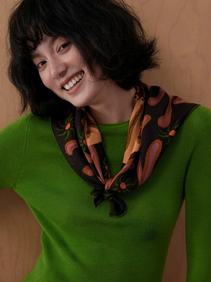 Woman wearing an espresso brown floral mulberry silk scarf knotted at the neck with a green sweater