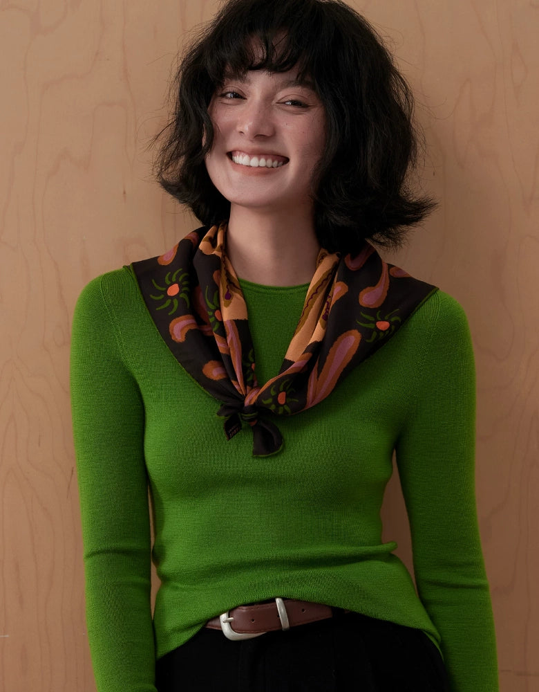 Front view of an espresso brown vintage floral silk scarf draped loosely over a green sweater