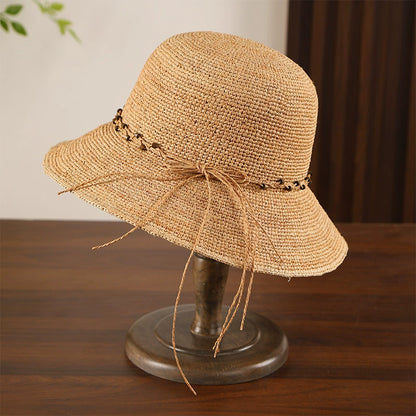 Fine crochet raffia sun hat with khaki bow trim, wide brim, and natural straw texture for summer travel.