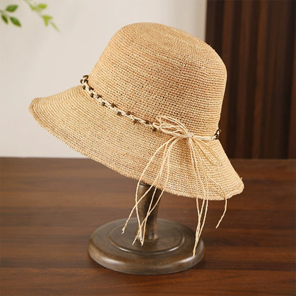 Beige bow raffia sun hat with fine crochet weave and wide brim, styled for beach vacation and resort wear.