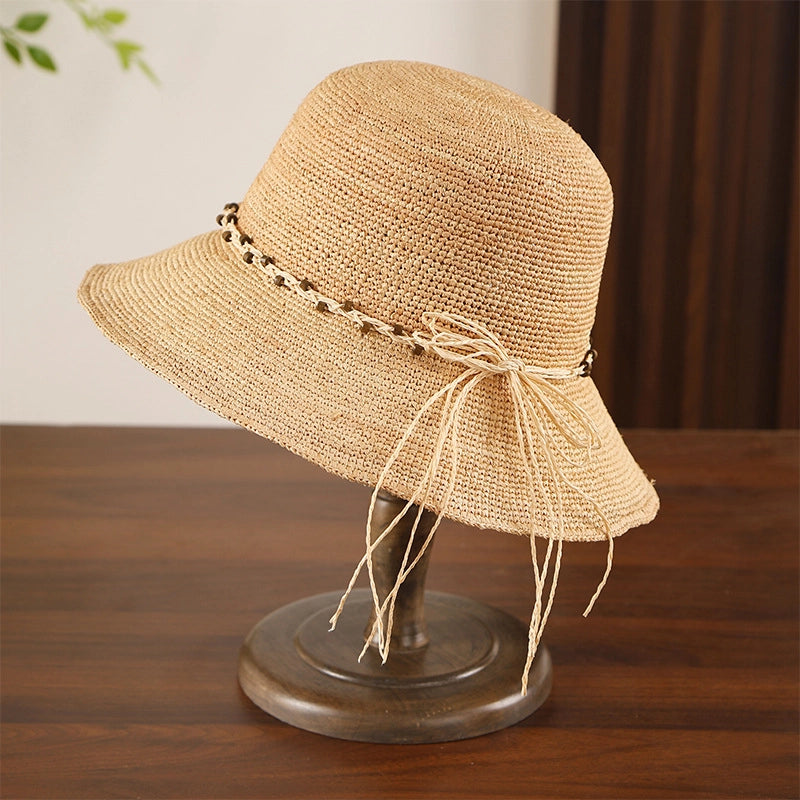 Fine crochet raffia sun hat with beige bow trim, wide brim, and breathable handmade texture for sunny days.