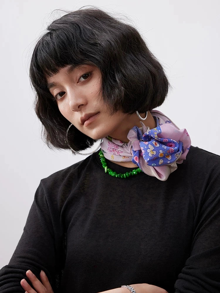 Pink mulberry silk scarf with floral dolphin print tied as a chic neck scarf.