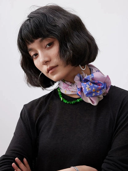 Pink mulberry silk scarf with floral dolphin print tied as a chic neck scarf.